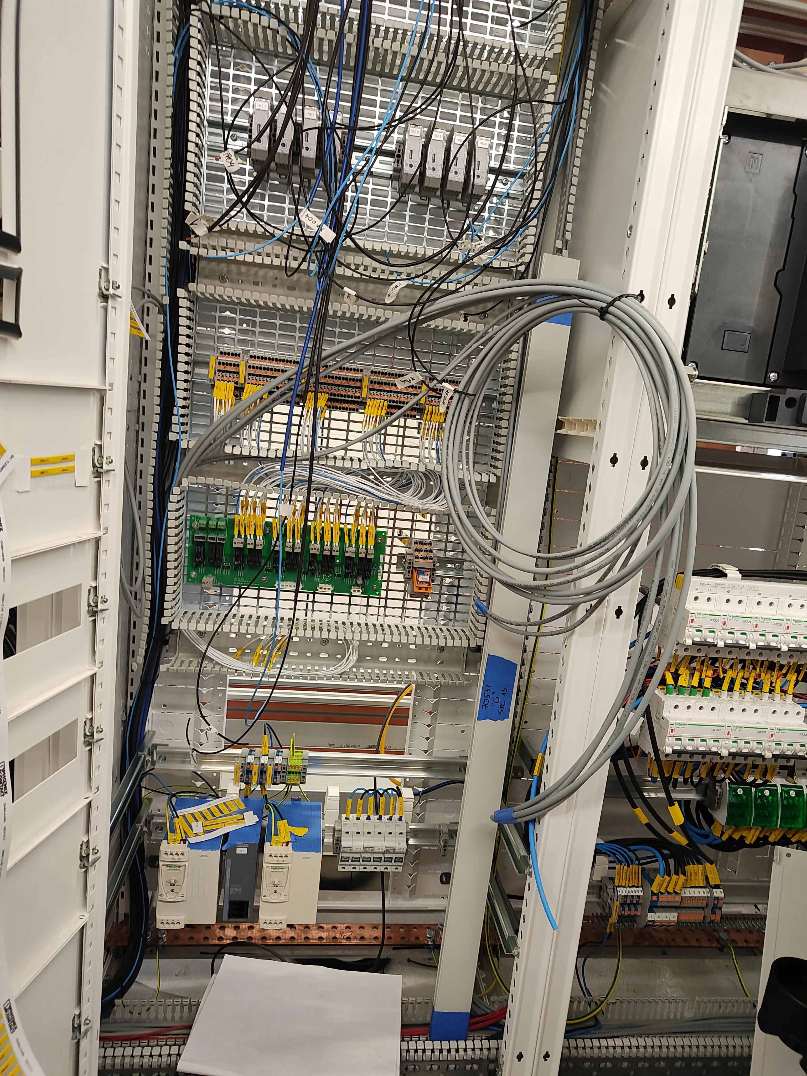 Szafa sterownicza z licznymi modułami, przekaźnikami i okablowaniem. Przykład kompleksowej instalacji elektrycznej.